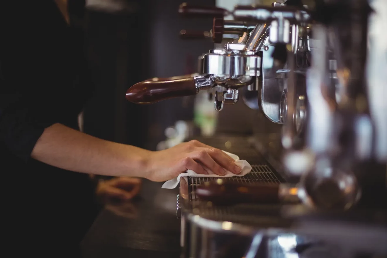 mid-section-waitress-wiping-espresso-machine-with-napkin-cafa-c